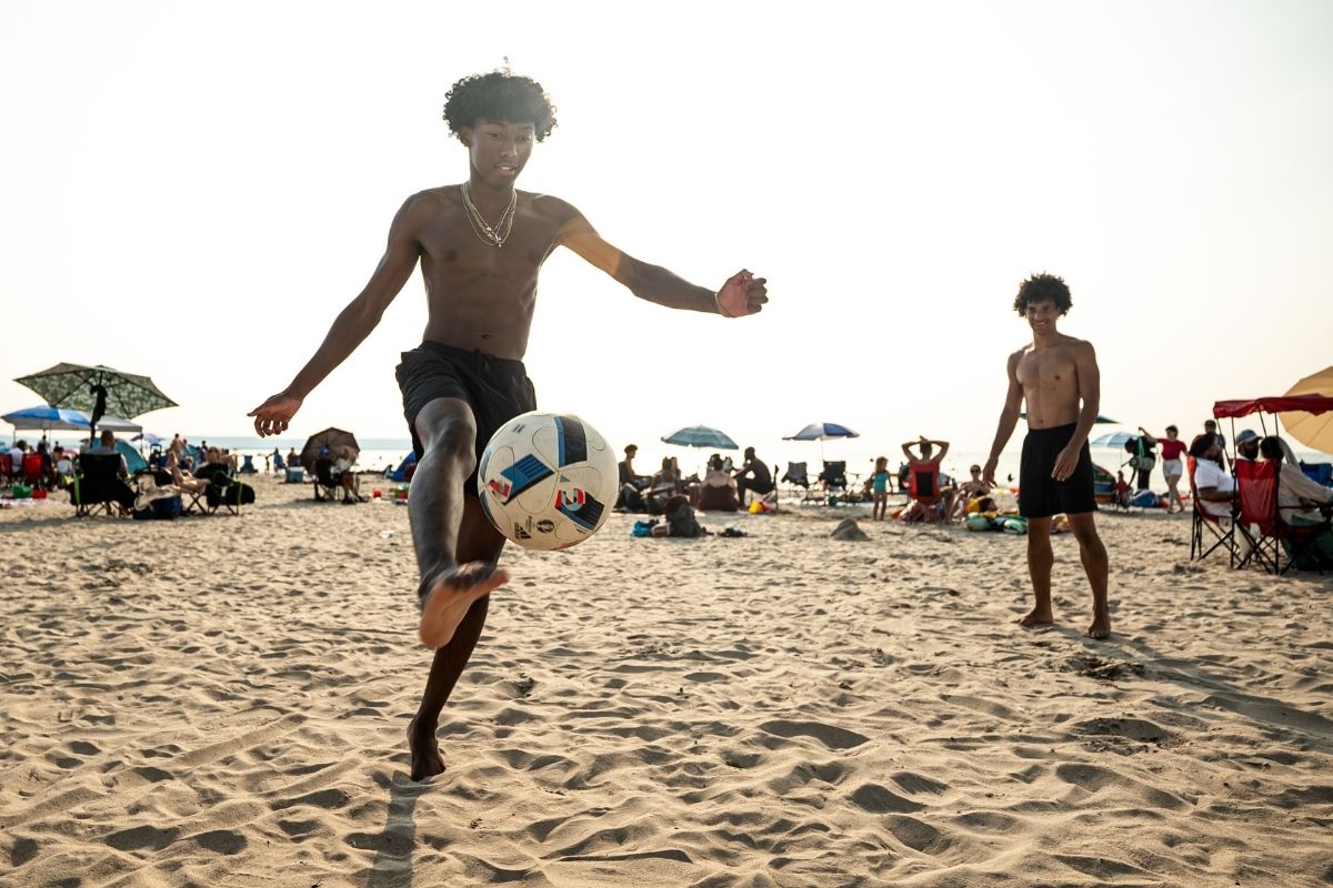 kids playing soccer on the beach